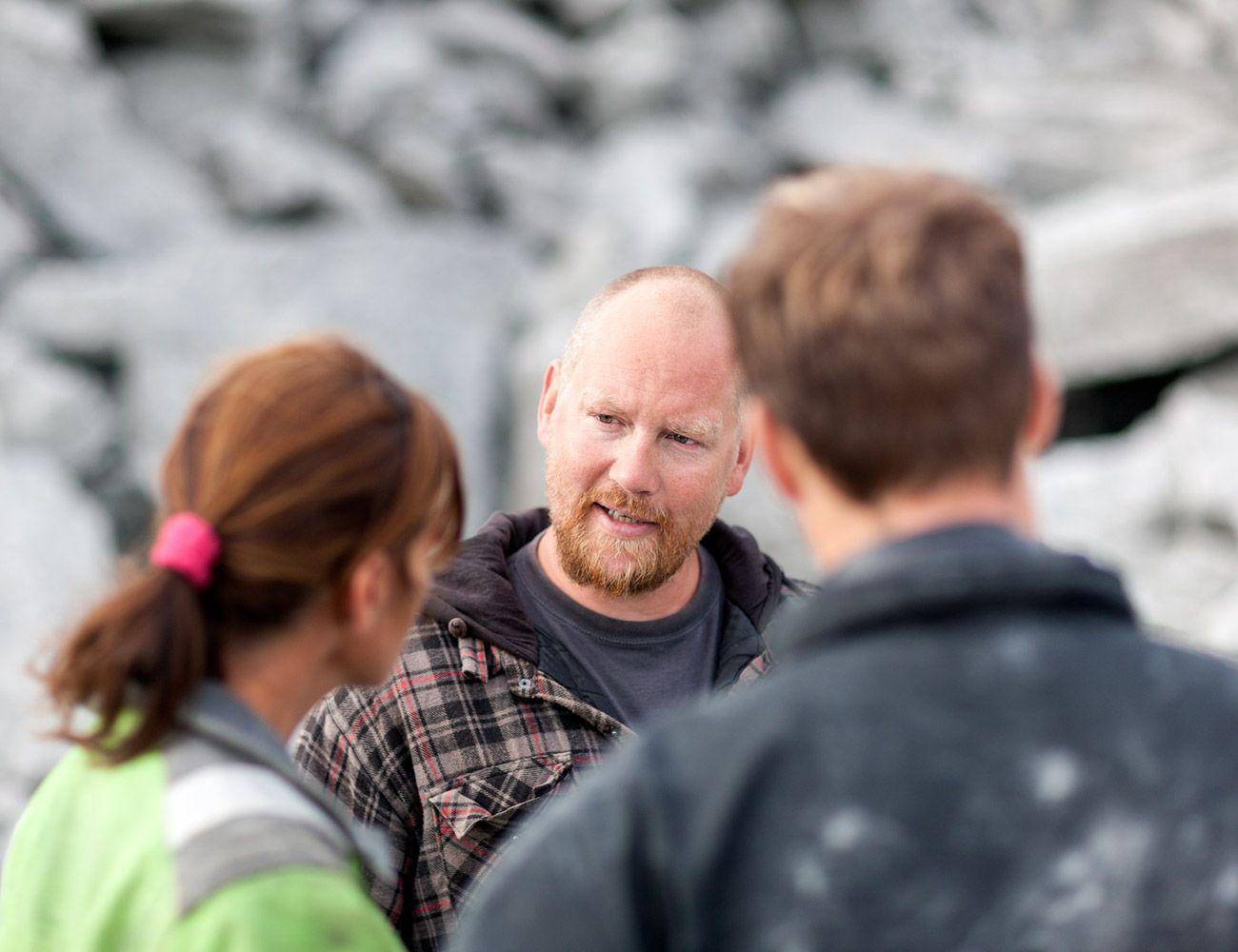 Three people talking at work site.