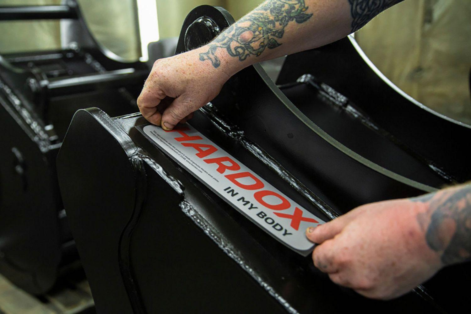 A person placing a Hardox® sign on a bucket.