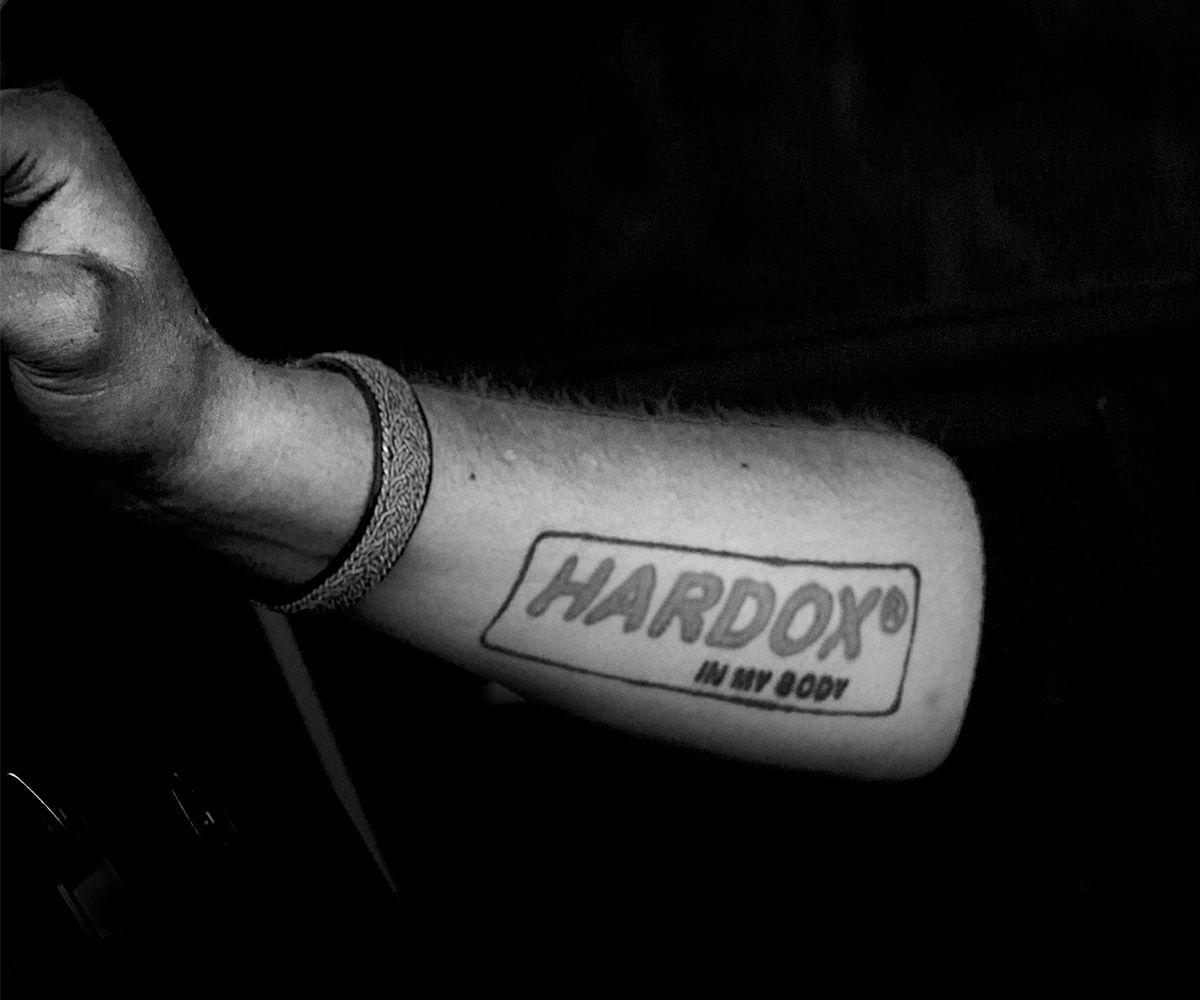 Black and white image of a persons forearm with a Hardox In My Body tattoo.