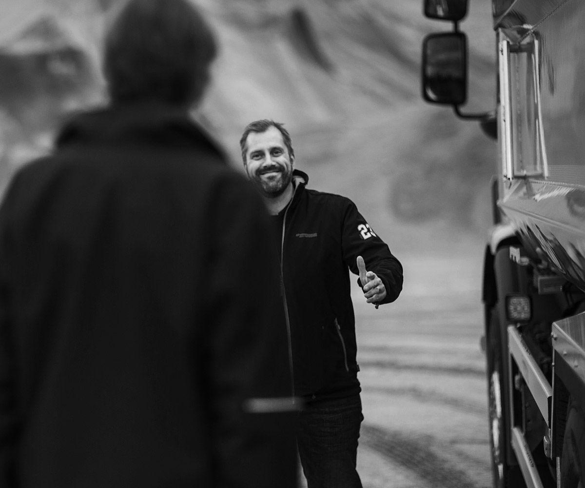 Black and white image of a happy man with another person in the foreground.